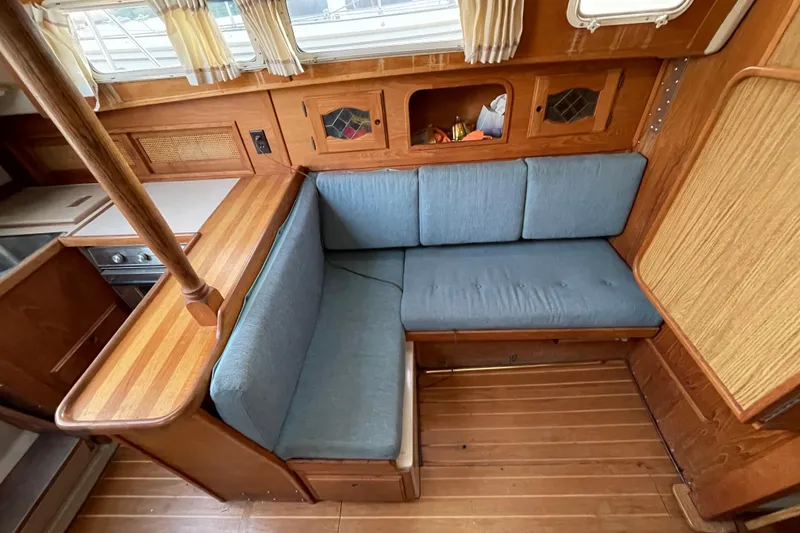 Slide: The Image of Cozy interior of 1987 Newport 30-3 sailboat with blue cushioned seating and wooden accents. - 10