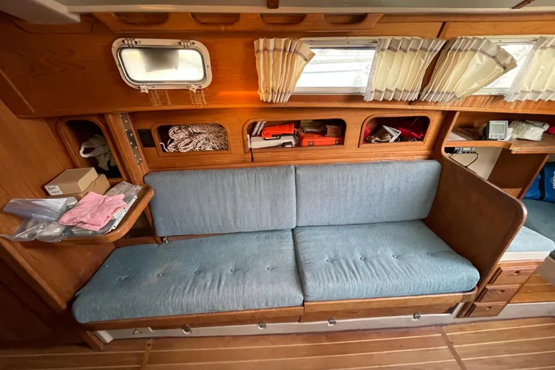 Slide: The Image of Interior of a 1987 Newport 30-3 sailboat with blue cushioned seating and wooden storage. - 11
