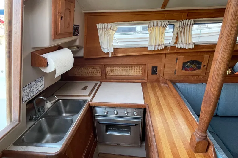 Slide: The Image of Cozy 1987 Newport 30-3 yacht interior with wooden kitchen, double sink, and stove. - 13