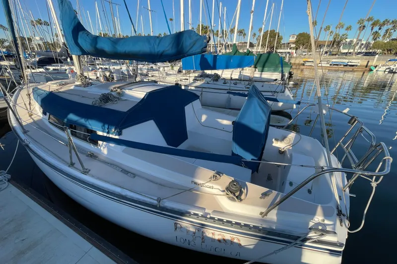 Slide: The Image of 1987 Newport 30 sailboat docked in marina, featuring blue covers and calm water reflections. - 2