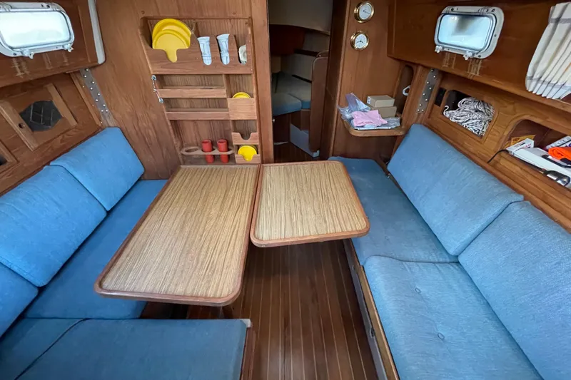 Slide: The Image of Interior of 1987 Newport 30-3 sailboat with blue seating and wooden table. - 9