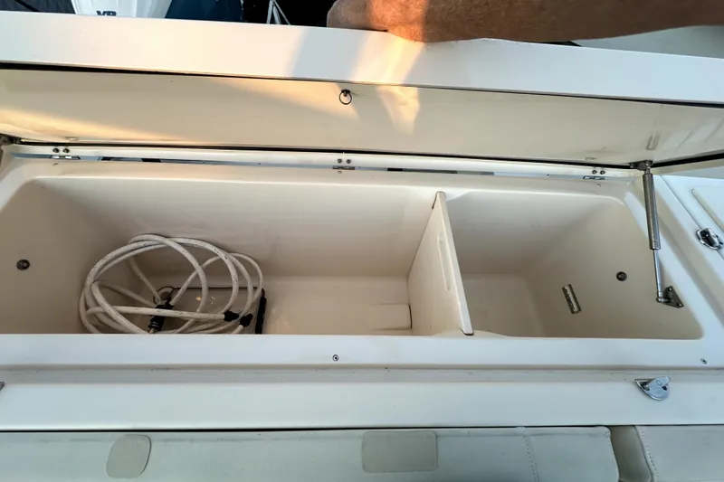 Slide: The Image of Open storage compartment on 2019 Grady-White Canyon 336 boat with coiled hose inside. - 35