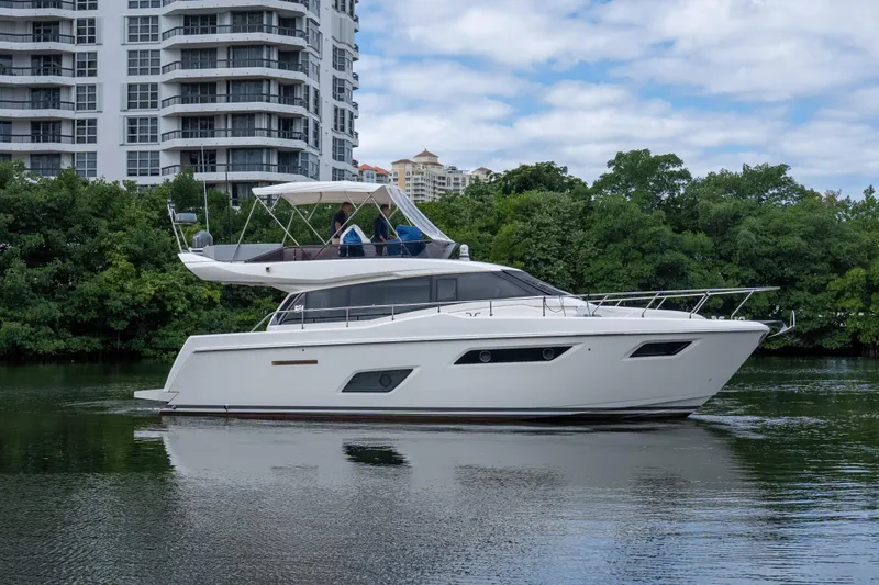 The Image of 2018 Ferretti Yachts 450 fly cruising near modern buildings and lush greenery. - 0