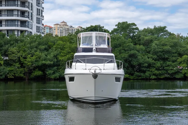 Slide: The Image of 2018 Ferretti Yachts 450 fly on calm water, surrounded by lush greenery and modern buildings. - 31