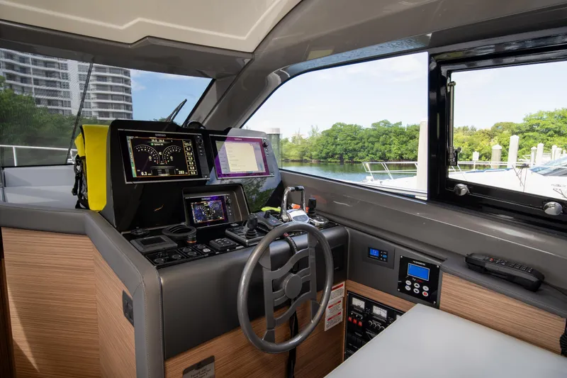 Slide: The Image of 2018 Ferretti Yachts 450 flybridge helm with modern navigation equipment and scenic marina view. - 6