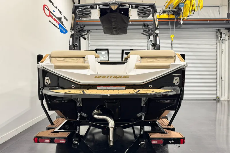 Slide: The Image of 2025 Nautique Super Air Nautique G21 boat rear view in showroom setting. - 4