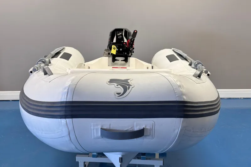 Slide: The Image of 2024 Caribe L-9 inflatable boat with motor, displayed indoors on a blue floor. - 3