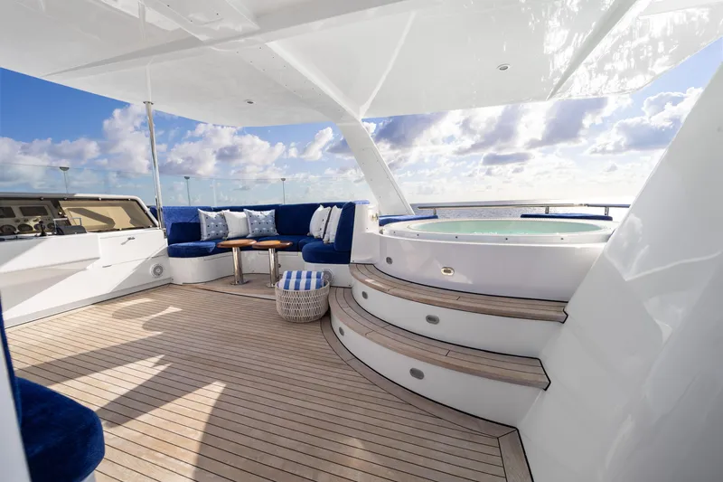 Slide: The Image of Luxurious 1990 Delta Expedition yacht deck with hot tub and blue seating under clear skies. - 40