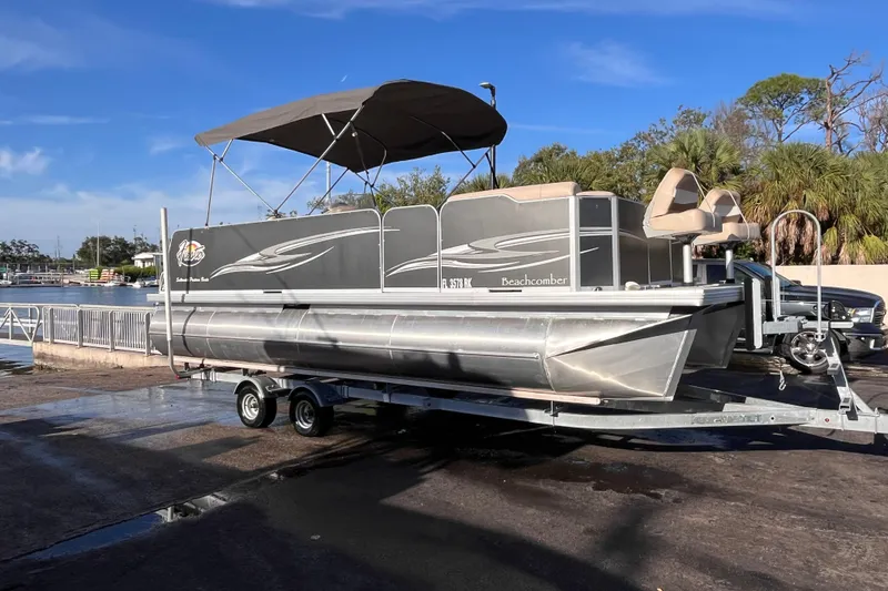 Slide: The Image of 2017 Fiesta 22 Beachcomber pontoon boat on trailer, parked near waterfront. - 1