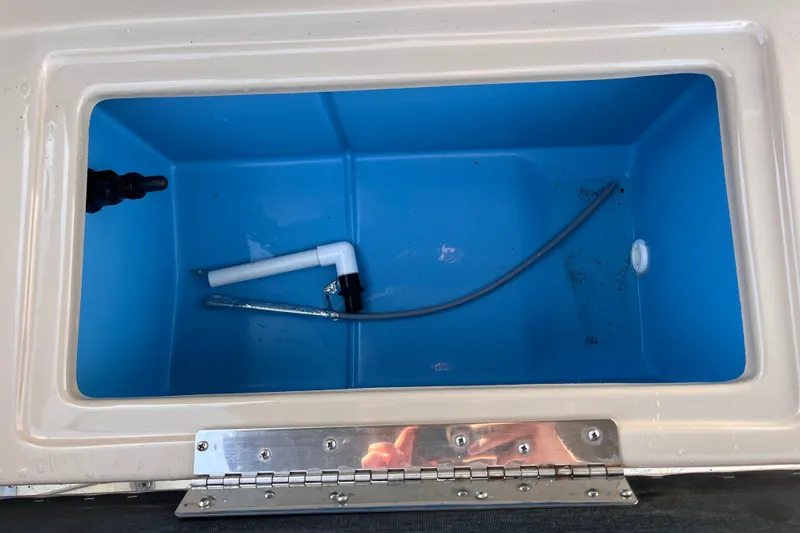 Slide: The Image of Open storage compartment in 2017 Fiesta 22 Beachcomber boat, featuring blue interior and plumbing components. - 17