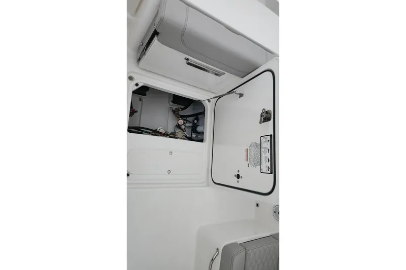 Slide: The Image of 2026 Pursuit DC 266 Dual Console interior storage compartment with visible wiring and components. - 33