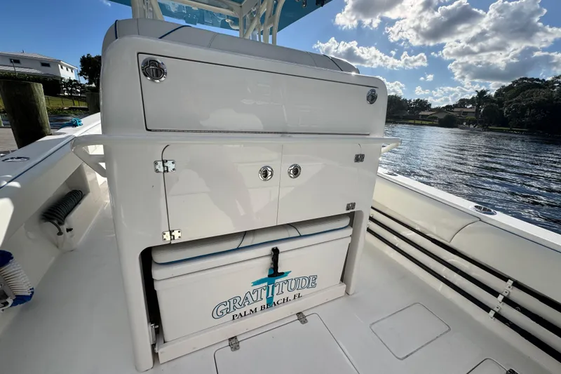 Slide: The Image of 2024 SeaVee 290B boat interior with storage and cooler, docked by a scenic waterfront. - 14