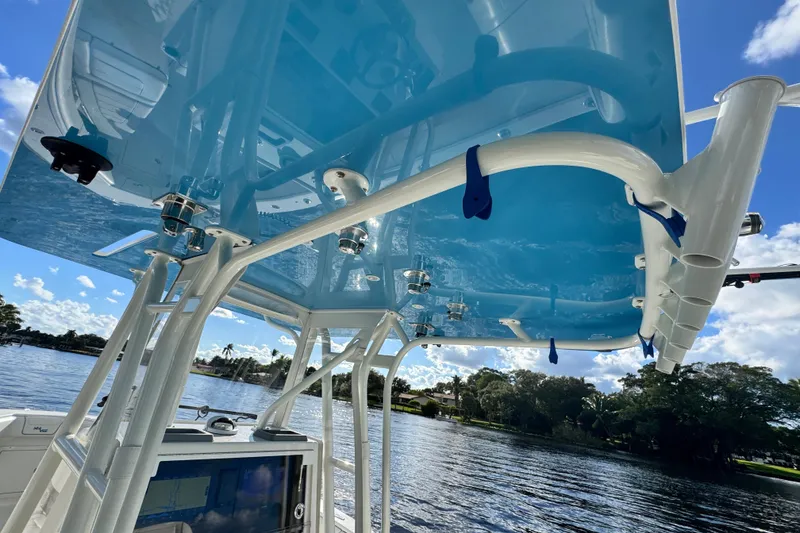 Slide: The Image of 2024 SeaVee 290B boat with blue canopy, rod holders, and scenic water view. - 18
