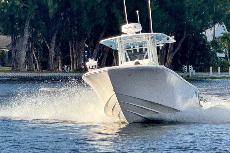 Slide: The Image of 2024 SeaVee 290B boat cruising on water, surrounded by lush trees. - 2