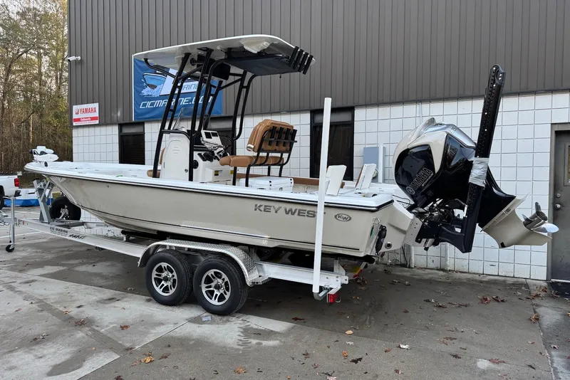 Slide: The Image of 2026 Key West 230 Bay Reef boat on trailer, parked outside a building. - 2