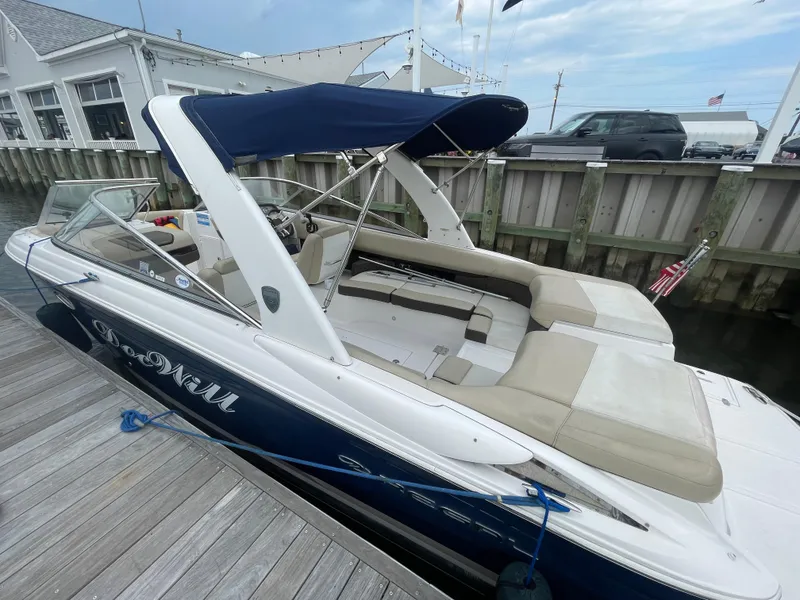 Slide: The Image of 2014 Regal 2700 Bowrider boat docked with blue canopy and beige seating. - 2
