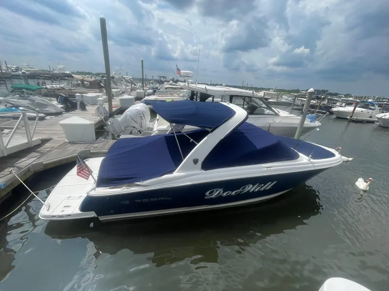 Slide: The Image of 2014 Regal 2700 Bowrider boat docked in marina, blue cover, cloudy sky. - 5