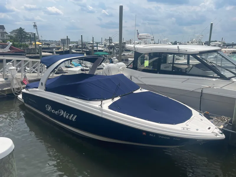 Slide: The Image of 2014 Regal 2700 Bowrider boat docked in marina, blue cover, calm waters. - 6
