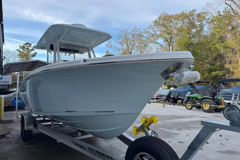 Slide: The Image of 2026 Key West 263 FS boat on trailer, parked outdoors, surrounded by trees and equipment. - 7
