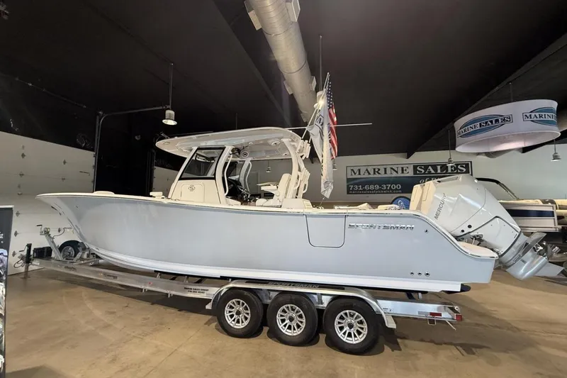 The Image of 2025 Sportsman Open 322 Center Console boat displayed in a showroom on a trailer. - 1