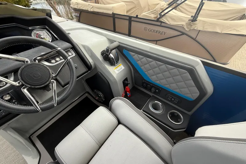 Slide: The Image of 2023 Godfrey AquaPatio 255 ULC boat interior with gray seating and cup holders. - 20