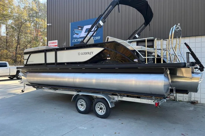 Slide: The Image of 2026 Godfrey SWEETWATER 2286 SFL pontoon boat on trailer, parked outdoors. - 2