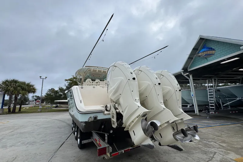 Slide: The Image of 2024 Grady-White Canyon 386 boat with triple outboard engines in a marina setting. - 18