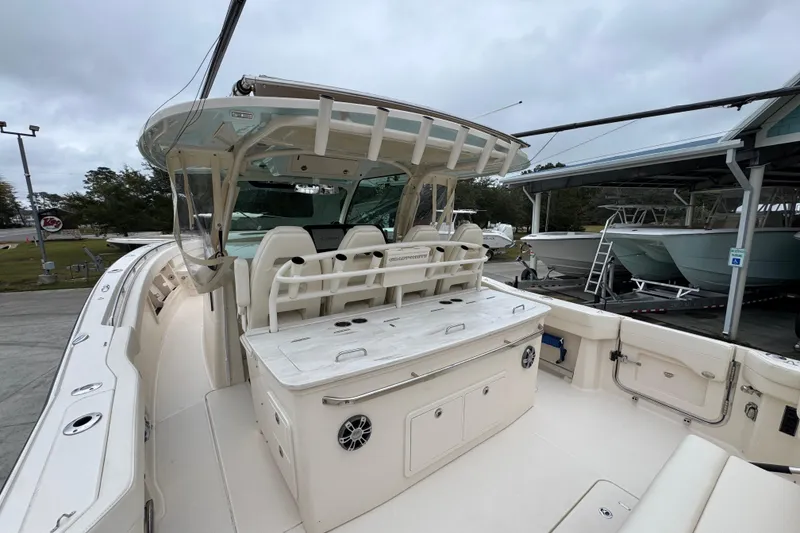 Slide: The Image of 2024 Grady-White Canyon 386 boat interior with seating and storage, docked under cloudy skies. - 54