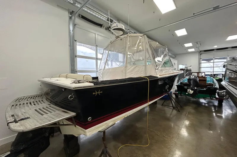 Slide: The Image of 2007 Hunt Yachts Harrier 25 in indoor storage, featuring a sleek black hull and protective cover. - 24
