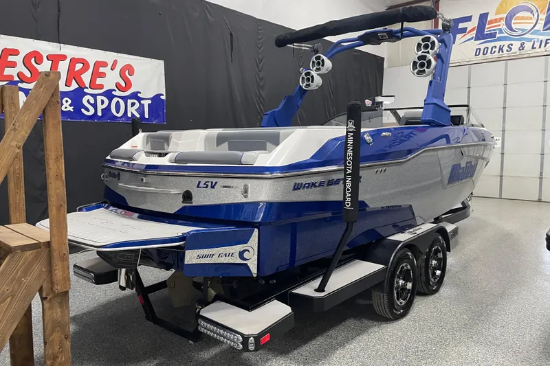 Slide: The Image of 2019 Malibu Wakesetter 25 LSV boat in showroom, blue and silver design, on trailer. - 2