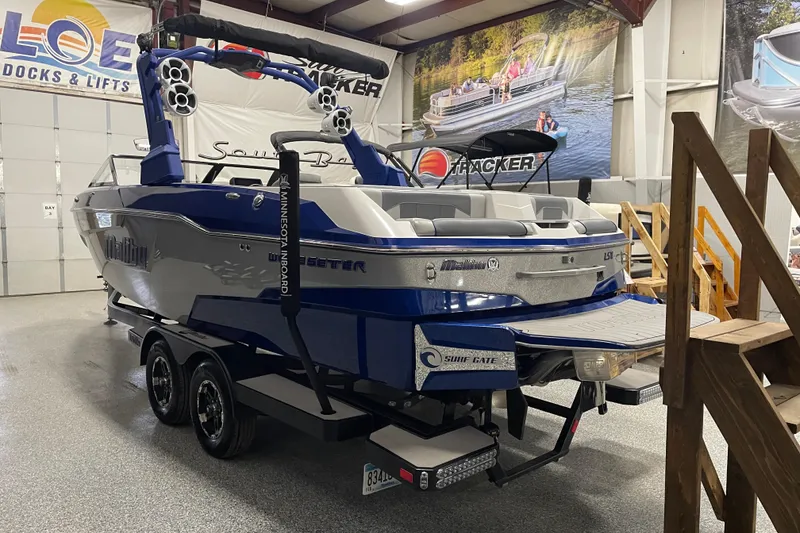 Slide: The Image of 2019 Malibu Wakesetter 25 LSV boat in showroom, blue and silver design, on trailer. - 3