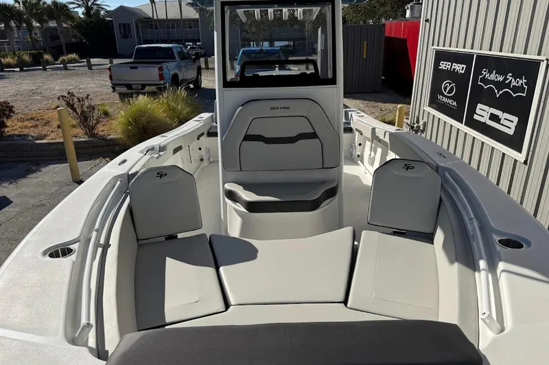 Slide: The Image of 2026 Sea Pro 245FLX Sandbar boat interior with seating and console, parked outdoors. - 4