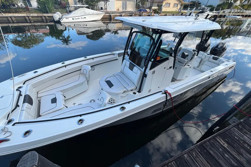 The Image of 2021 Wellcraft 302 Scarab boat docked in a scenic waterfront setting. - 1