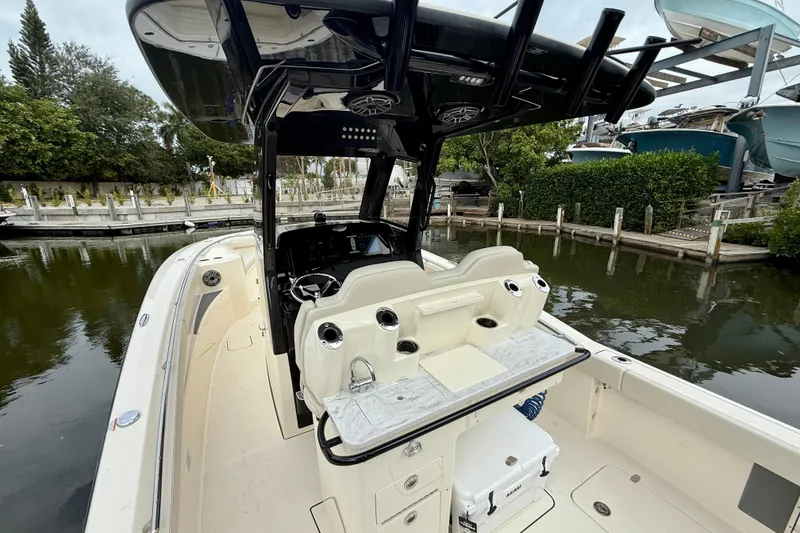 Slide: The Image of 2026 Scout 288 LXF boat interior with helm and seating, docked by lush greenery. - 13