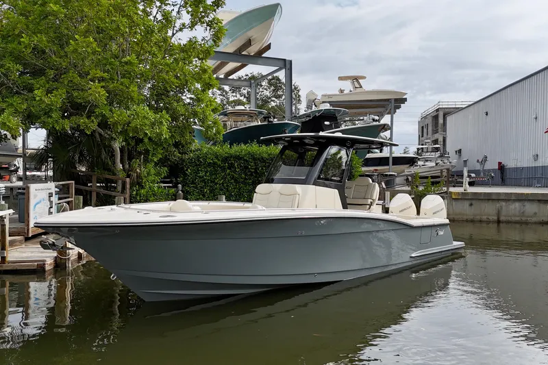Slide: The Image of 2026 Scout 288 LXF boat docked near marina, surrounded by trees and buildings. - 3