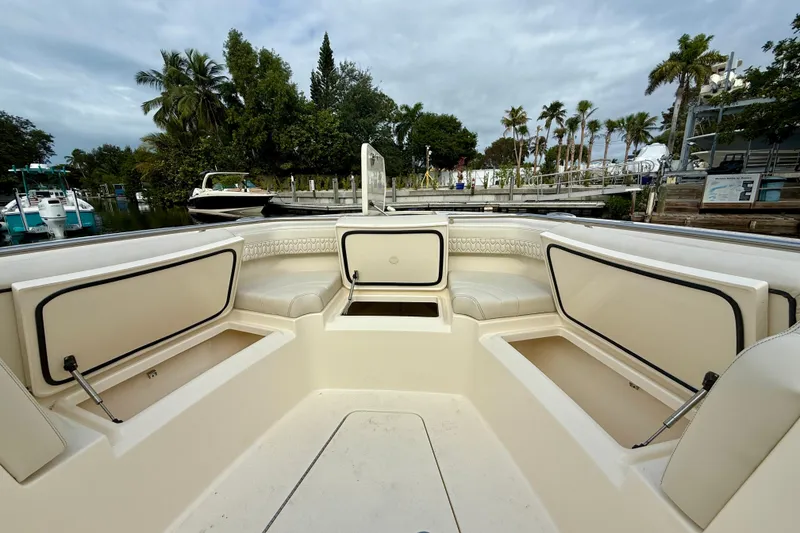 Slide: The Image of 2026 Scout 288 LXF boat interior with seating and storage, docked near palm trees. - 9