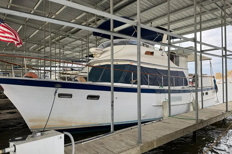 The Image of 1991 DeFever 44 yacht docked in a covered marina with American flag. - 1