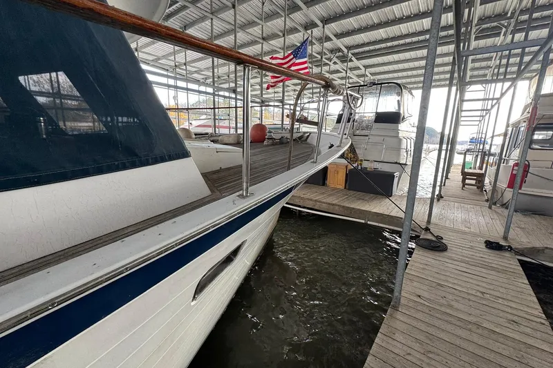 Slide: The Image of 1991 DeFever 44 yacht docked under a covered marina with American flag. - 15