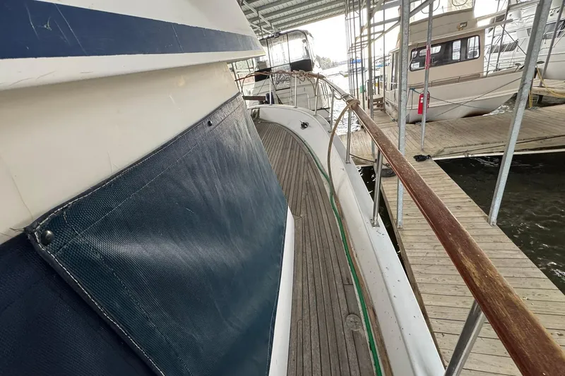 Slide: The Image of 1991 DeFever 44 yacht docked, showcasing wooden deck and protective side covering. - 35