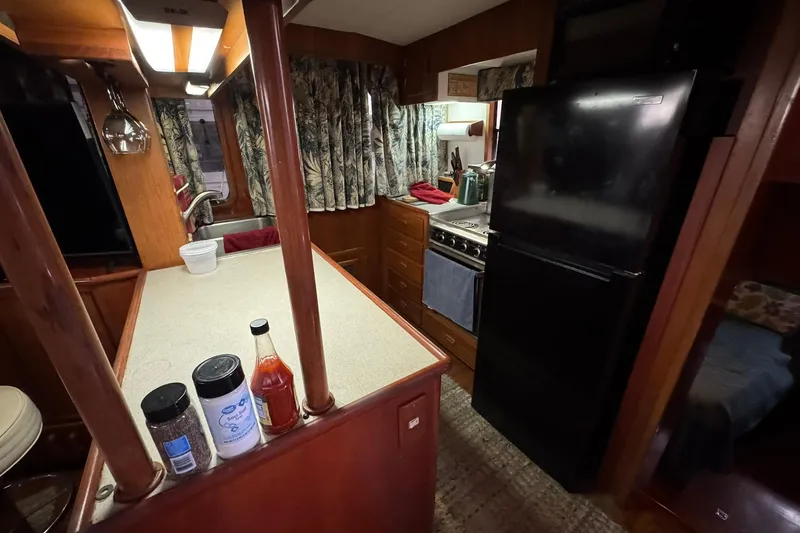 Slide: The Image of 1991 DeFever 44 yacht kitchen with black fridge, stove, and wooden cabinetry. - 38