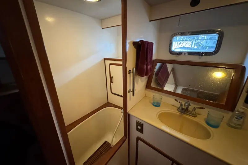 Slide: The Image of Bathroom of 1991 DeFever 44 yacht with sink, mirror, and porthole window. - 55