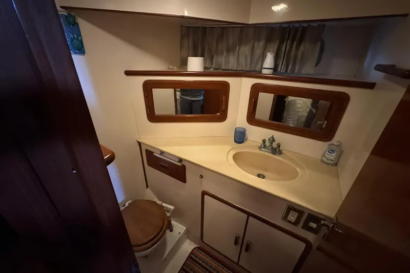 Slide: The Image of 1991 DeFever 44 yacht bathroom with sink, mirrors, and wooden accents. - 65