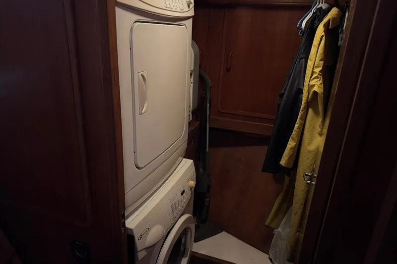 Slide: The Image of Laundry area with stacked washer-dryer and hanging coats on a 1991 DeFever 44 boat. - 67