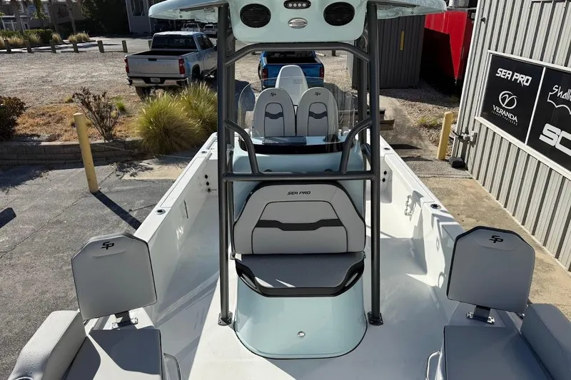Slide: The Image of 2026 Sea Pro 250 Bay boat interior with seating and console, parked outdoors. - 23