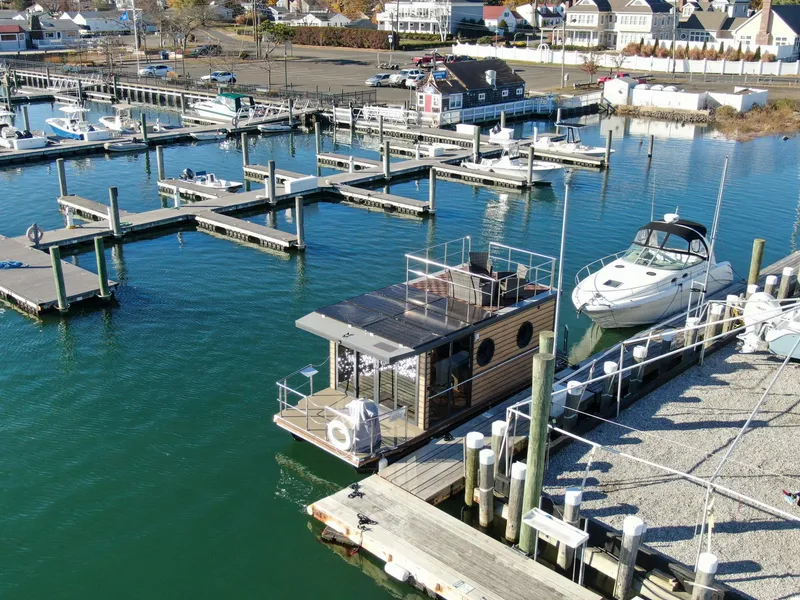 Slide: The Image of Modern Waterlodge Apart M 2024 houseboat docked in a marina with surrounding boats. - 28