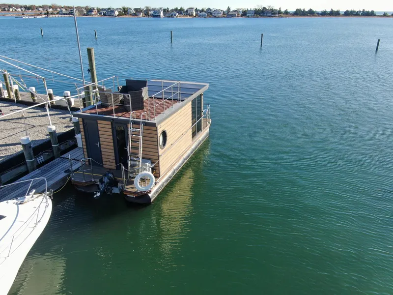 Slide: The Image of Houseboat Waterlodge Apart M 2024 docked on calm water, with scenic shoreline view. - 3