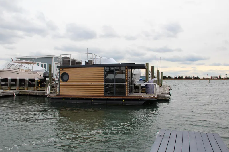 Slide: The Image of Modern 2024 Waterlodge Apart M houseboat docked on a serene waterfront. - 4