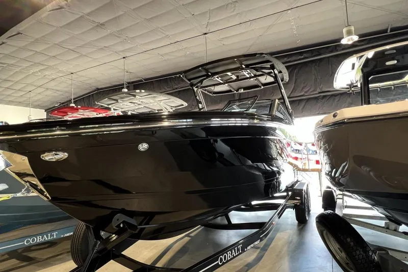The Image of 2026 Cobalt R8 Surf boat in showroom, sleek black design, on trailer. - 10