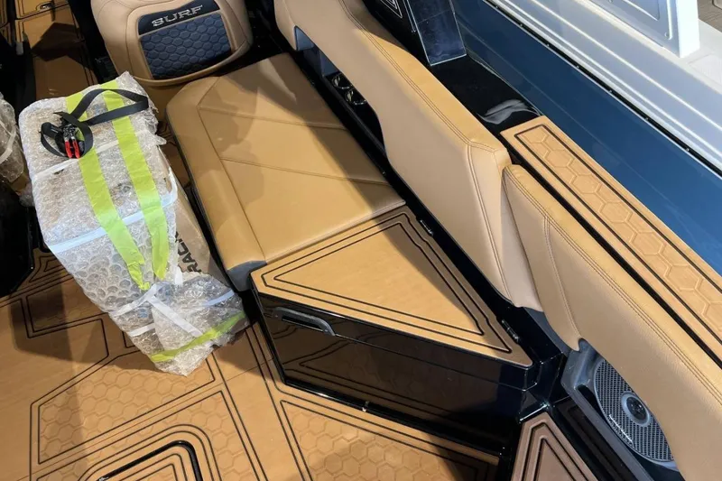 Slide: The Image of 2026 Cobalt R8 Surf boat interior with tan seating and bubble-wrapped package. - 15