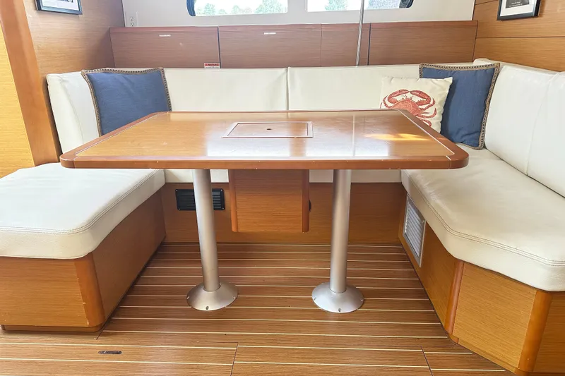 Slide: The Image of 2015 Jeanneau Sun Odyssey 469 interior with wooden table and white cushioned seating. - 20